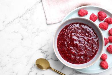 Photo of Delicious jam and fresh raspberries on white marble table, flat lay. Space for text