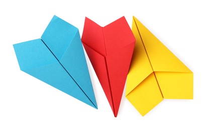 Photo of Handmade yellow, light blue and red paper planes isolated on white, top view