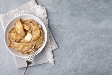 Photo of Delicious dumplings (varenyky) with cottage cheese and butter served on light grey table, top view. Space for text