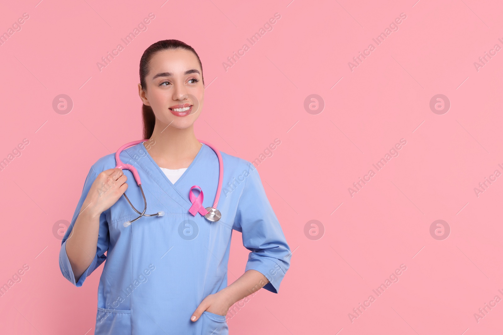 Photo of Mammologist with pink ribbon on color background, space for text. Breast cancer awareness