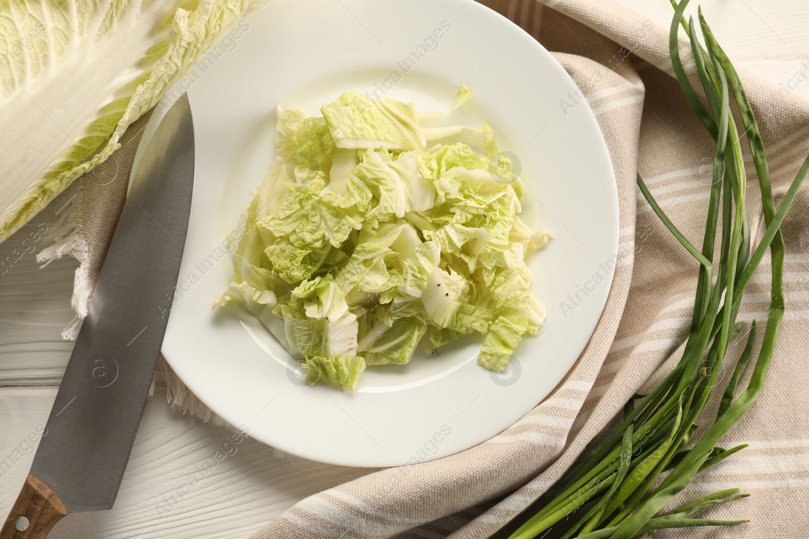 Photo of Cut fresh Chinese cabbage, green onion and knife on white wooden table, flat lay