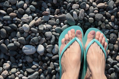 Woman in stylish flip flops on pebble beach, closeup. Space for text