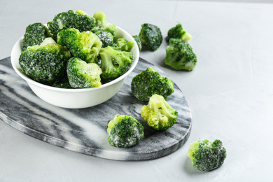 Photo of Frozen broccoli florets on light grey table. Vegetable preservation