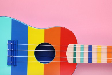 Colorful ukulele on pink background, top view. String musical instrument