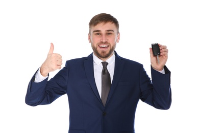 Happy young businessman with car key on white background