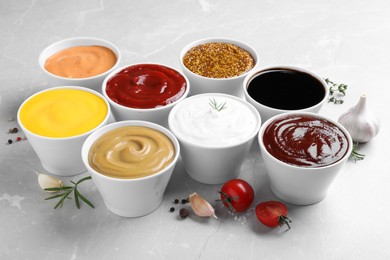 Photo of Many bowls with different sauces on light grey table