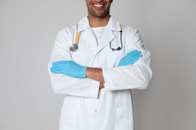 Doctor or medical assistant (male nurse) in uniform with stethoscope on light grey background, closeup