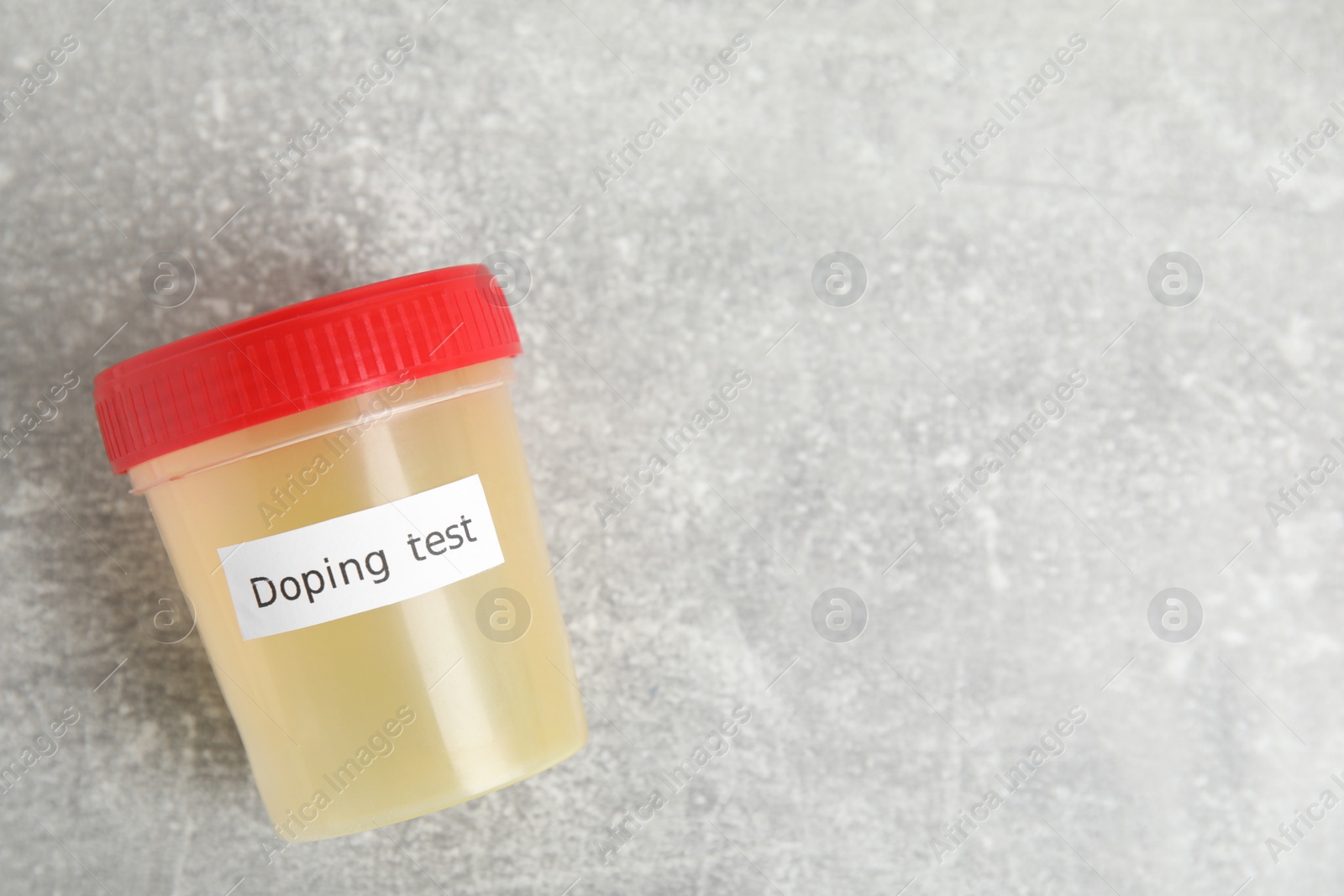 Photo of Jar of urine with words Doping test on light grey stone table, top view. Space for text