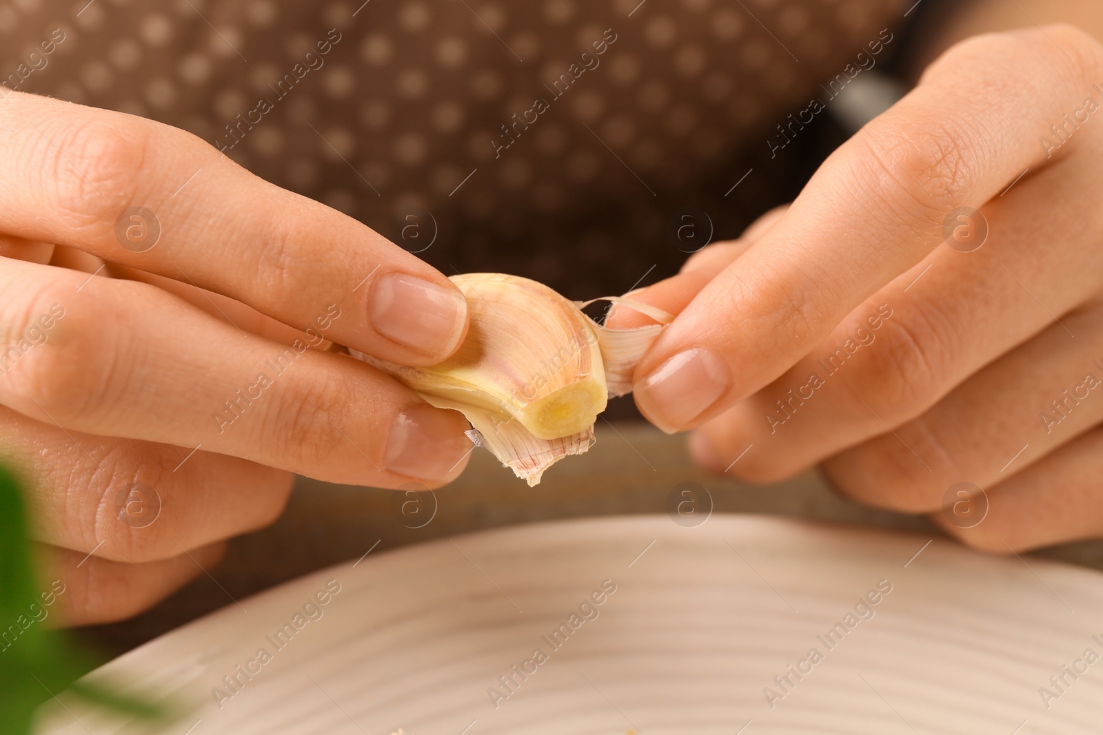 Photo of Woman peeling fresh garlic at table, selective focus