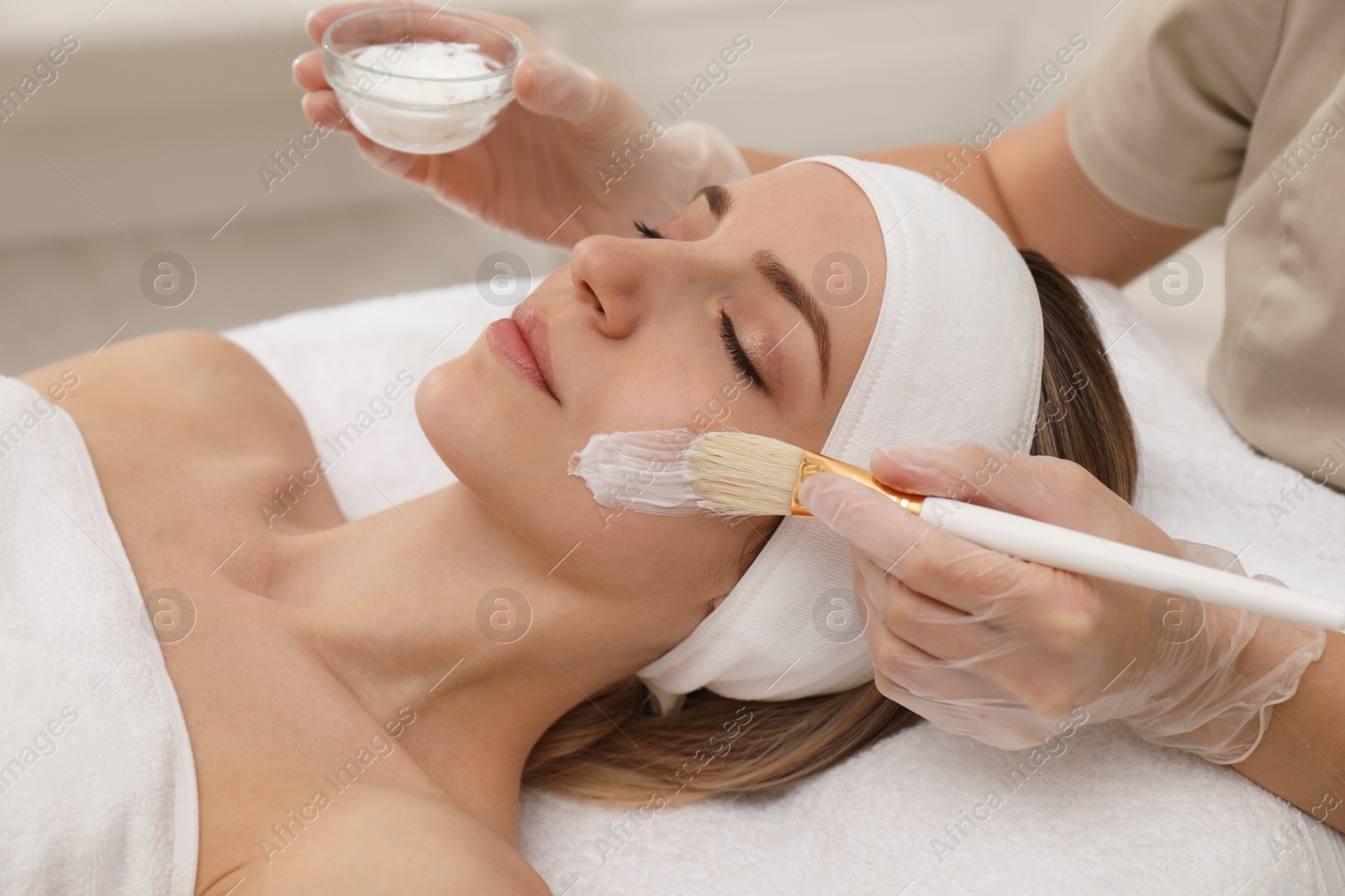 Photo of Young woman during face peeling procedure in salon