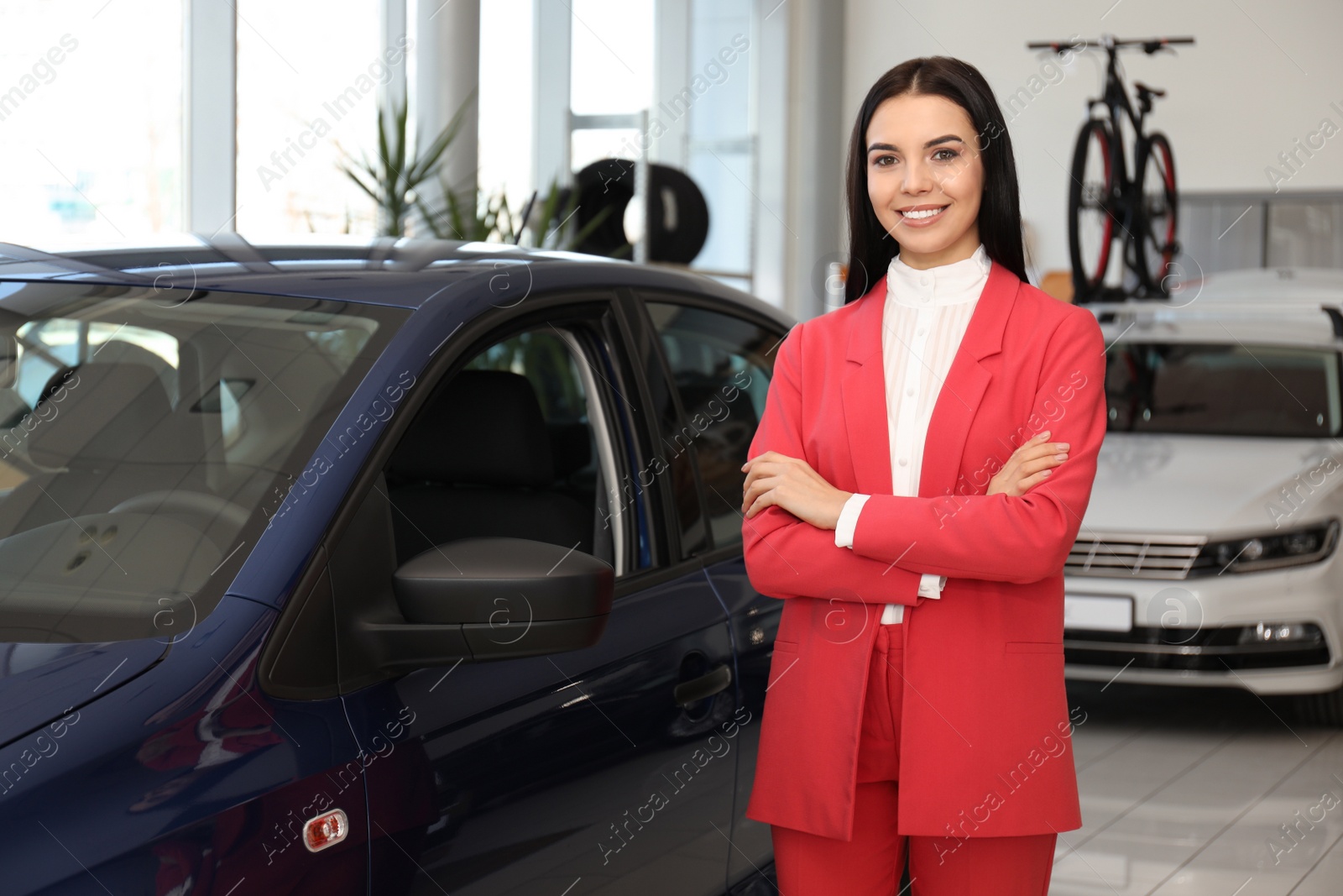 Photo of Young saleswoman near new car in dealership