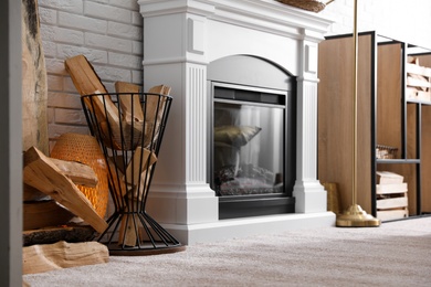 Photo of Firewood in holder near modern fireplace in living room