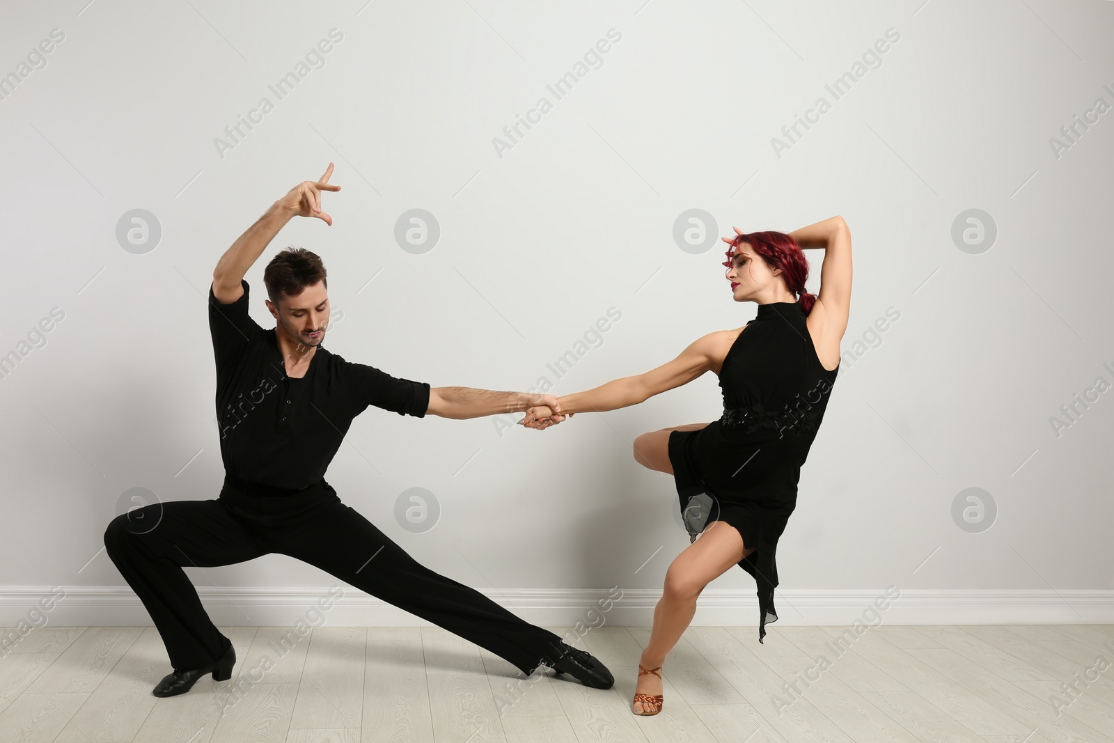 Photo of Beautiful young couple dancing near light wall