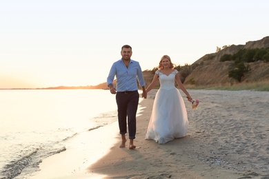 Photo of Wedding couple. Bride and groom walking at sunset on beach