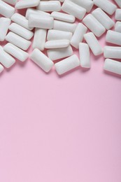 Photo of Tasty white chewing gums on pale pink background, flat lay. Space for text