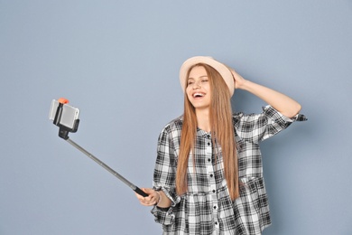 Young beautiful woman taking selfie against grey background