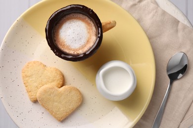 Delicious edible biscuit cup with coffee, milk and heart shaped cookies on table, flat lay