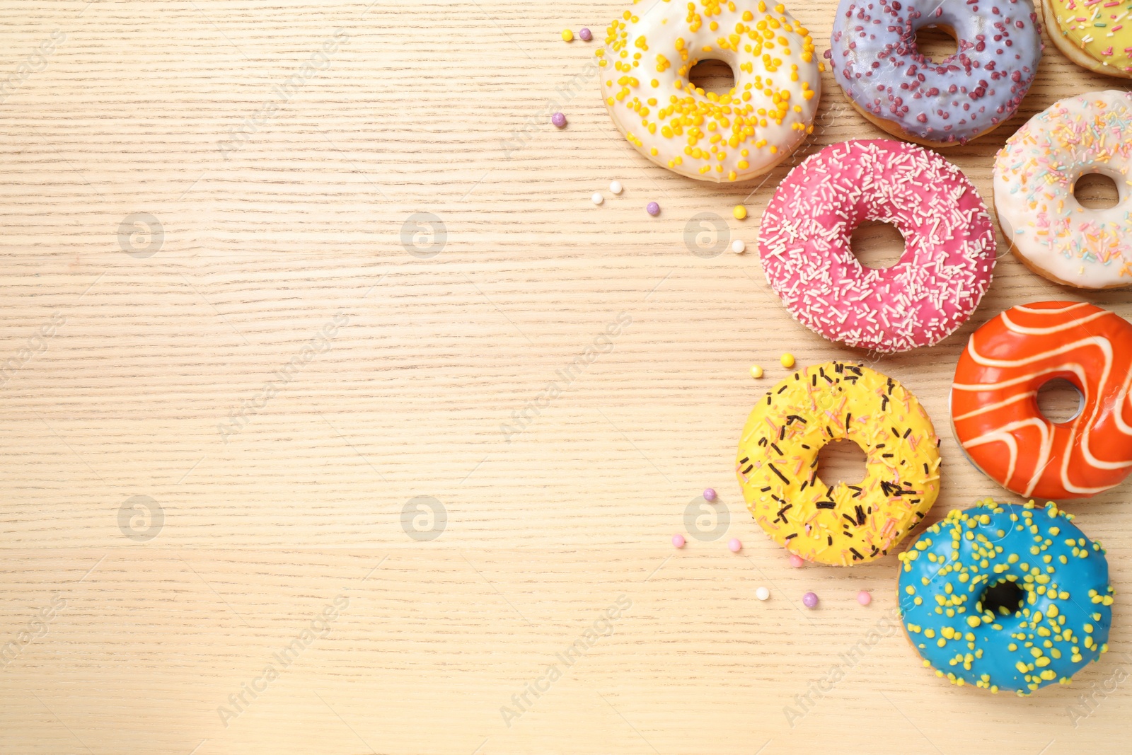 Photo of Delicious glazed donuts on wooden table, flat lay. Space for text