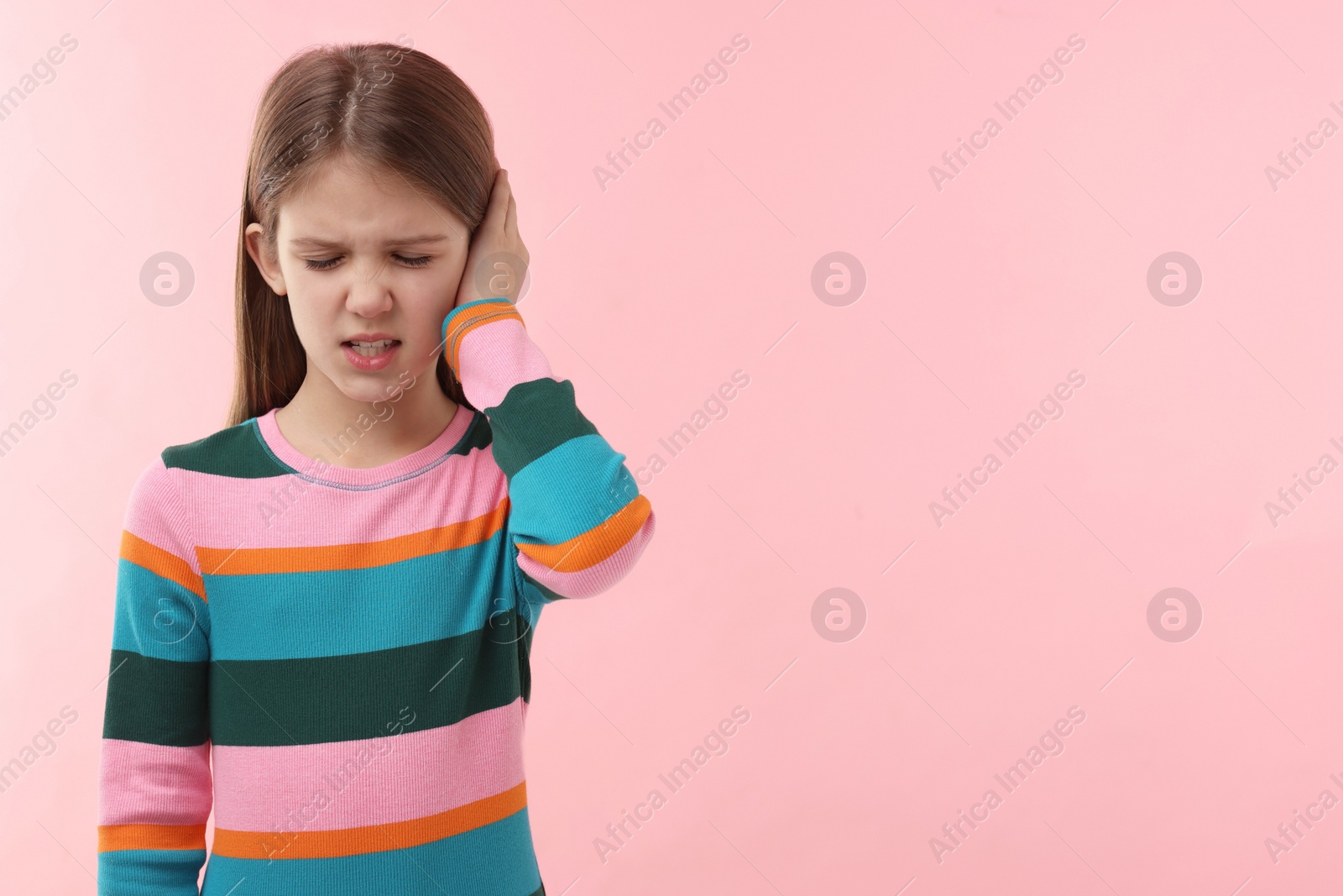 Photo of Hearing problem. Little girl suffering from ear pain on pink background, space for text