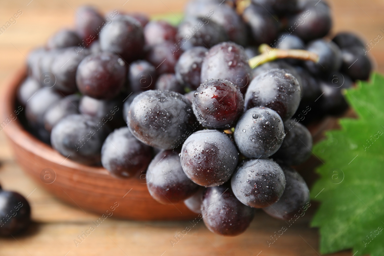 Photo of Fresh ripe juicy grapes in bowl on table, closeup