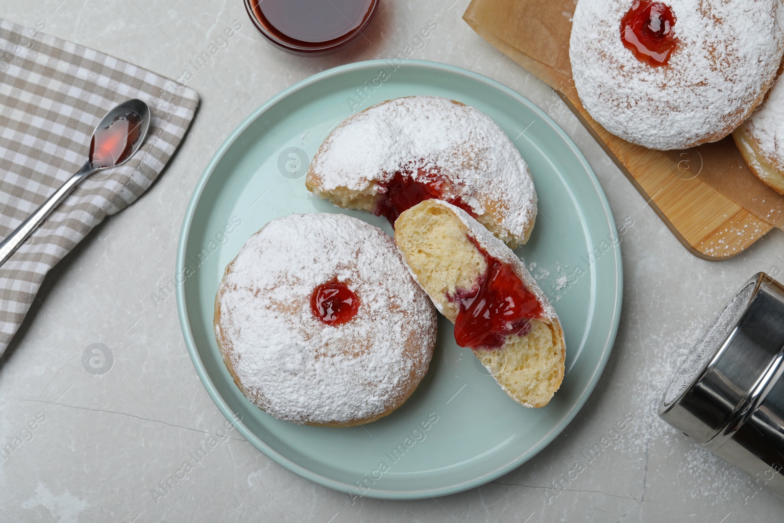 Photo of Delicious donuts with jelly and powdered sugar served on light grey table, flat lay