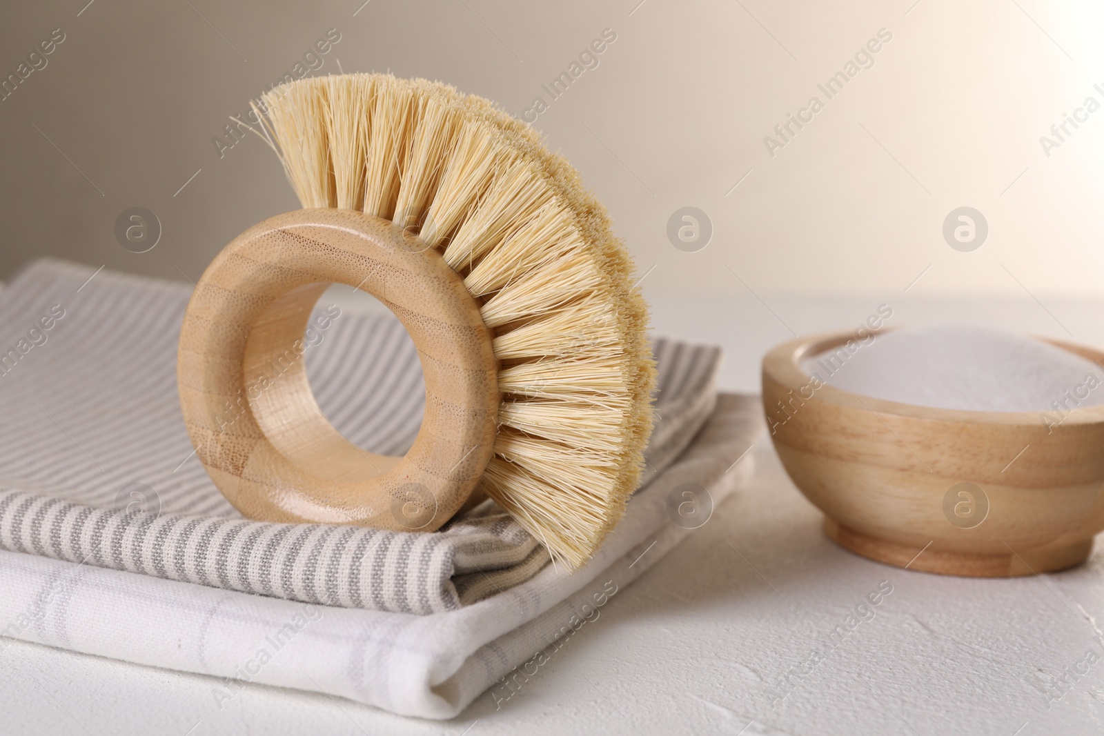 Photo of One cleaning brush, detergent and cloth on white textured table, closeup