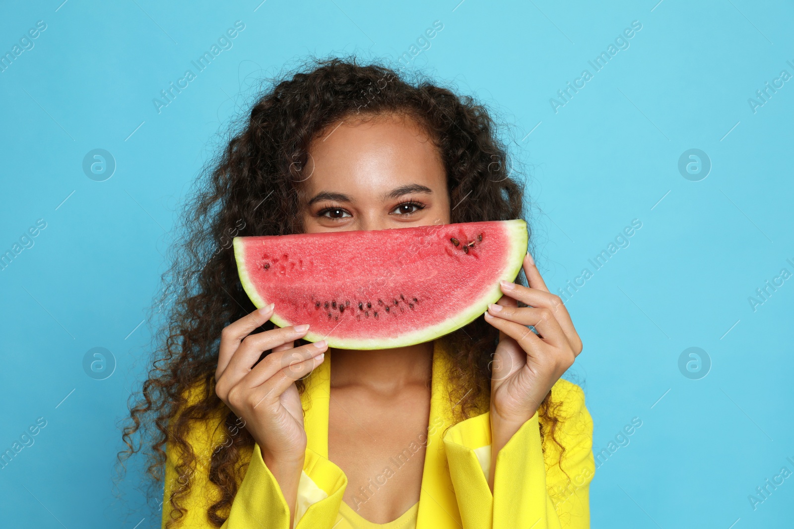 Photo of Beautiful young African American woman with watermelon on light blue background