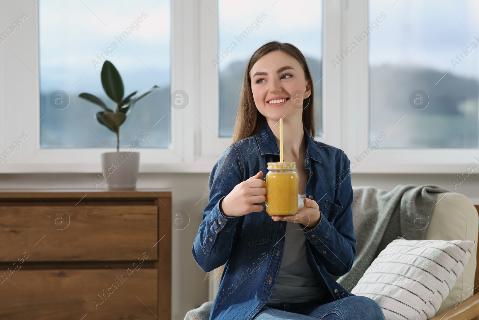 Photo of Beautiful young woman with delicious smoothie at home. Space for text