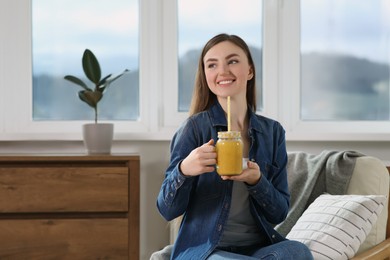 Beautiful young woman with delicious smoothie at home. Space for text