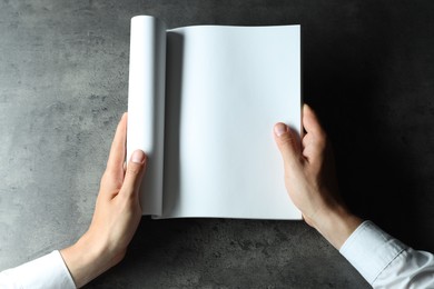 Photo of Man holding blank notebook at black textured table, top view. Mockup for design