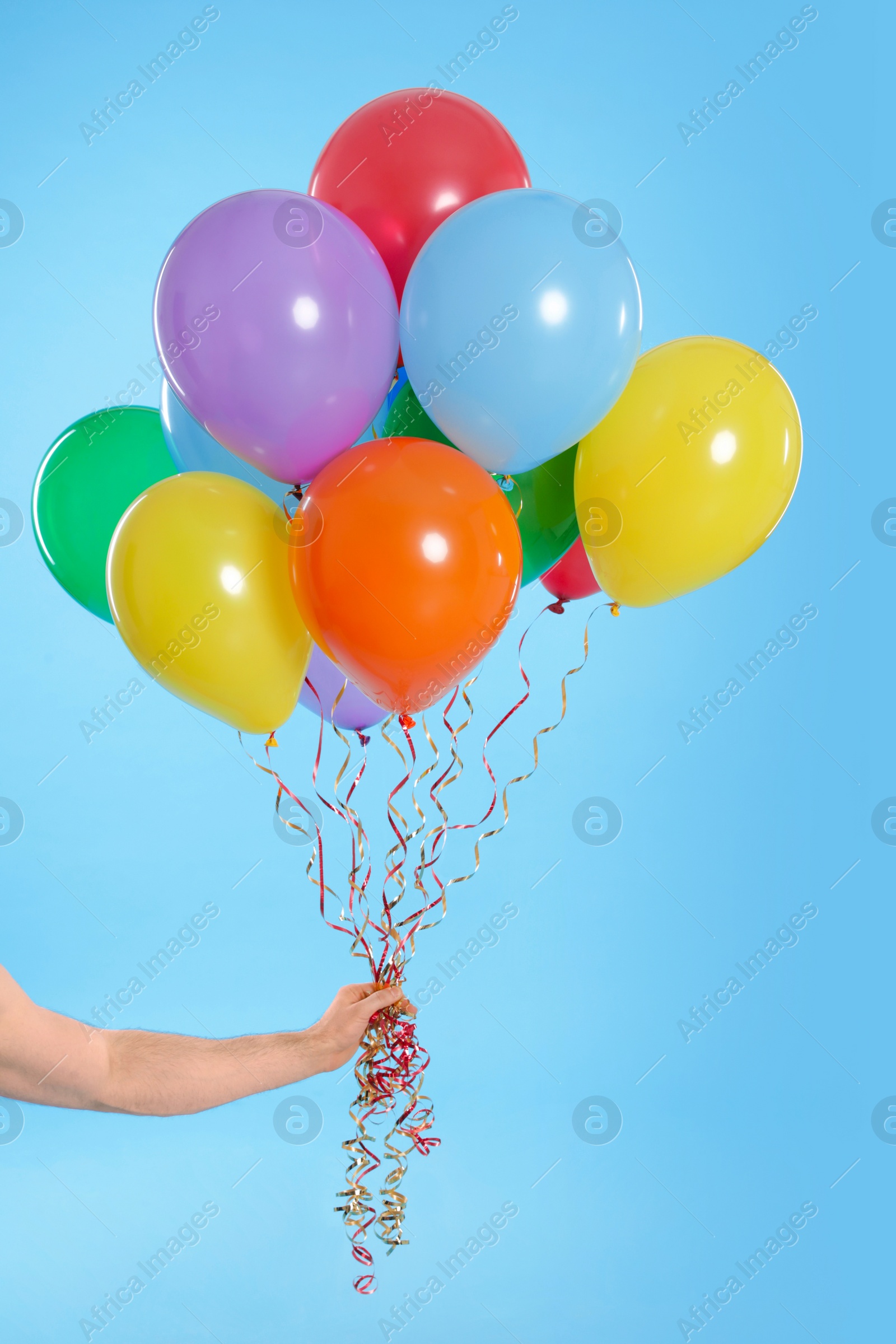 Photo of Man holding bunch of balloons on color background, closeup