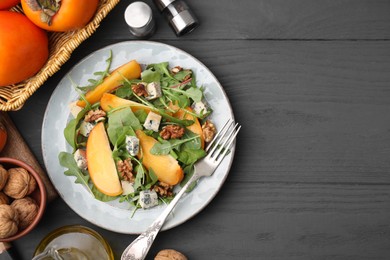 Tasty salad with persimmon, blue cheese and walnuts served on grey wooden table, flat lay. Space for text