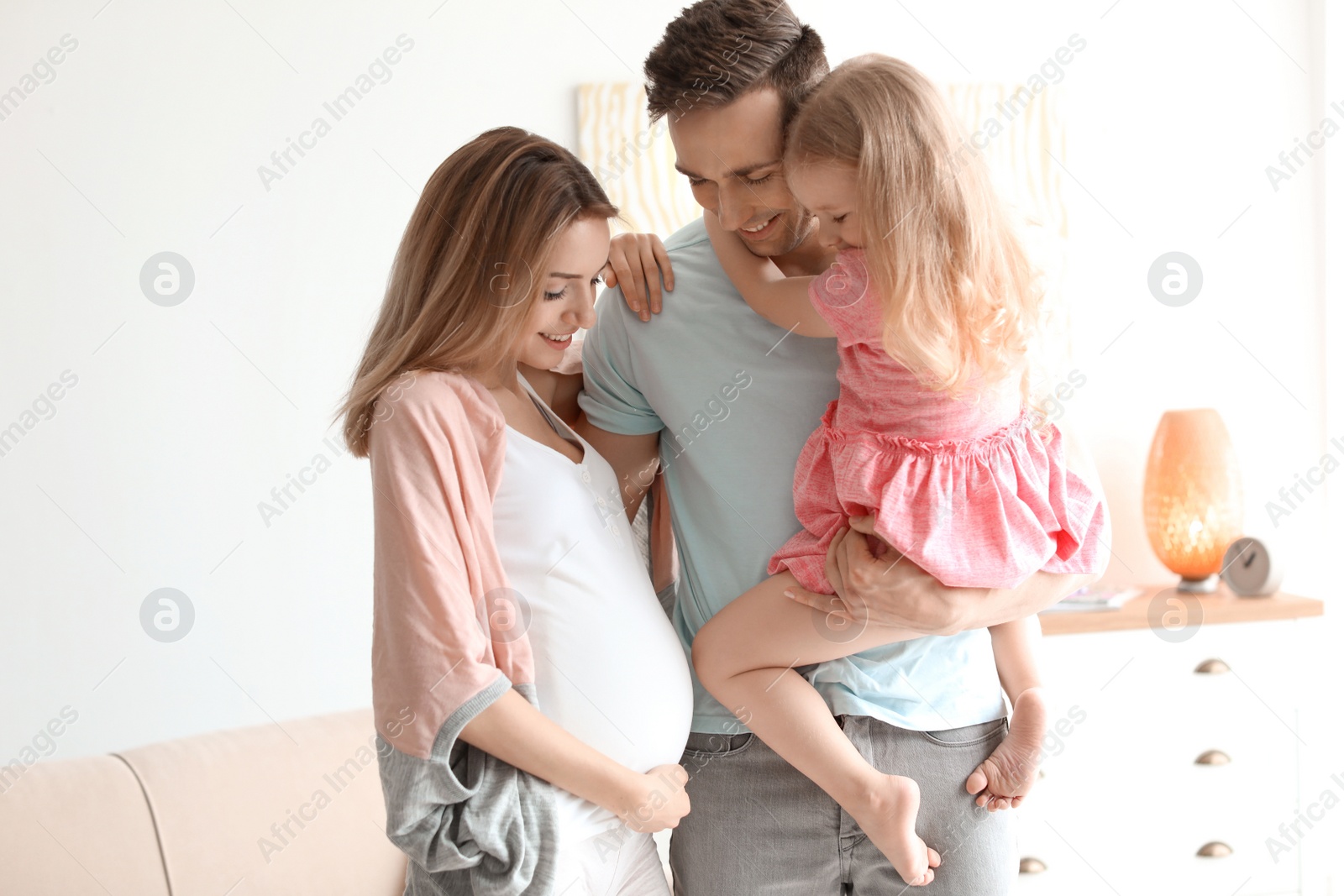 Photo of Young pregnant woman with her family at home