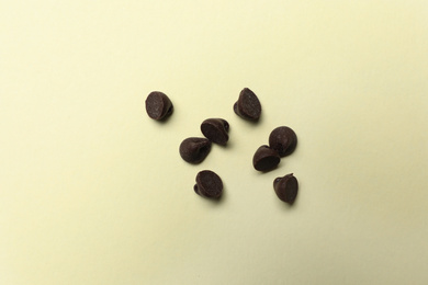 Delicious chocolate chips on beige background, top view