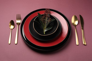 Photo of Stylish table setting with cutlery and floral decor on pink background