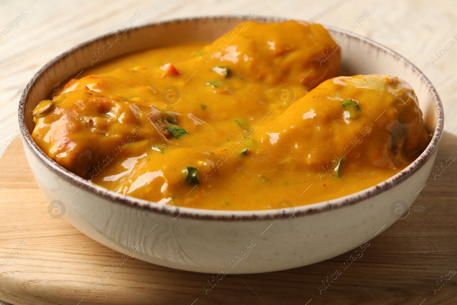 Photo of Tasty chicken curry on wooden table, closeup