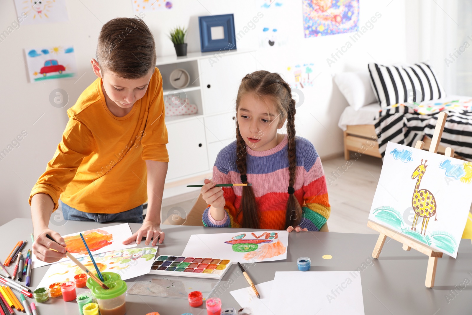 Photo of Little children painting picture at table indoors