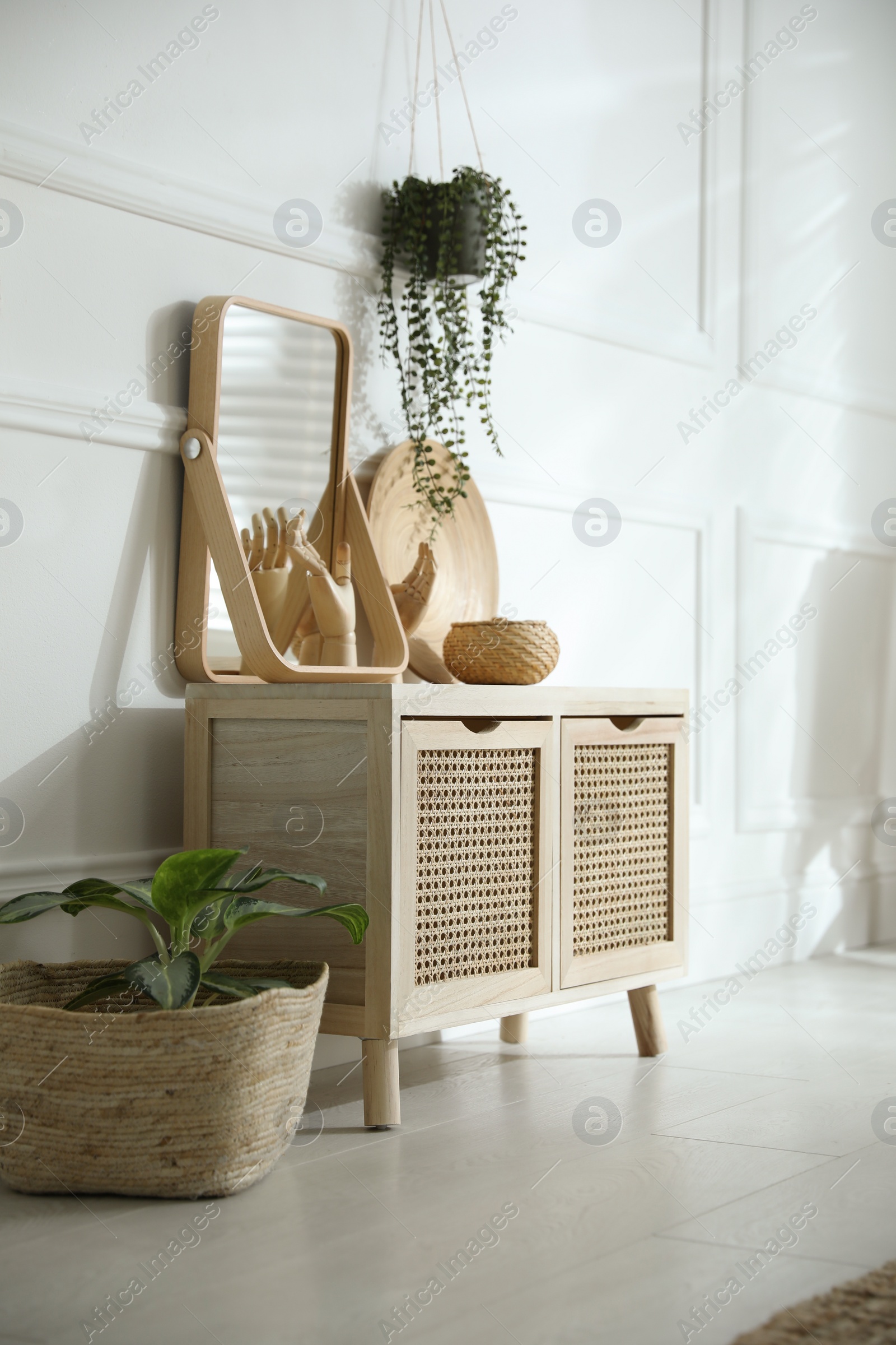 Photo of Wooden commode near white wall in room. Interior design