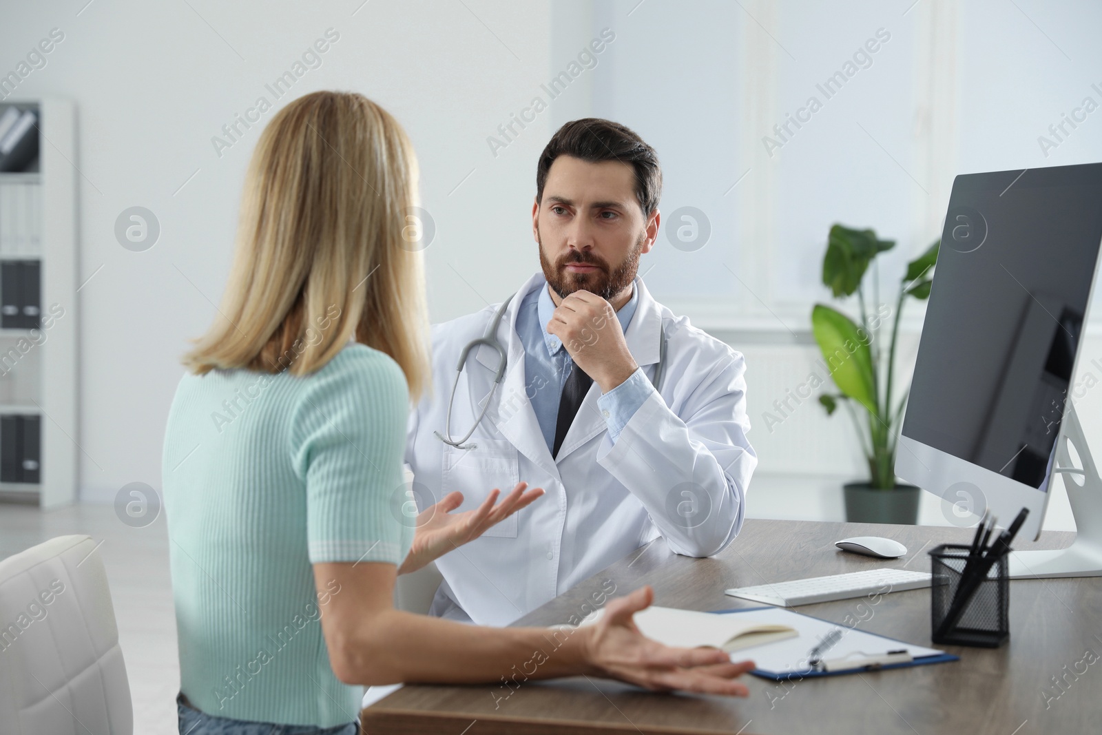 Photo of Doctor consulting patient at wooden table in clinic