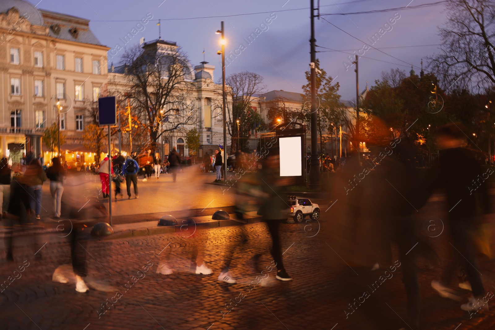 Photo of People crossing city street at evening, long exposure effect