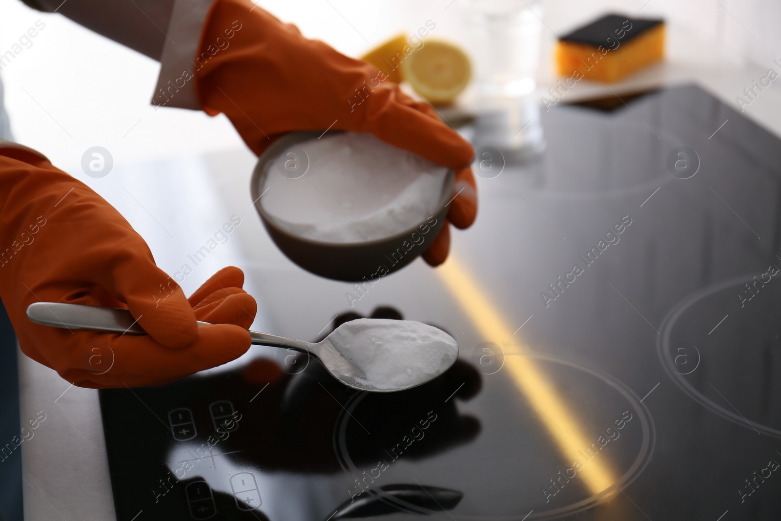 Photo of Woman using baking soda to clean electric cooktop, closeup. Wrong detergent for such surfaces