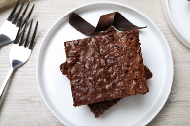 Delicious chocolate brownies served on white wooden table, flat lay