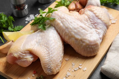 Photo of Fresh raw chicken wings and other products on wooden board, closeup