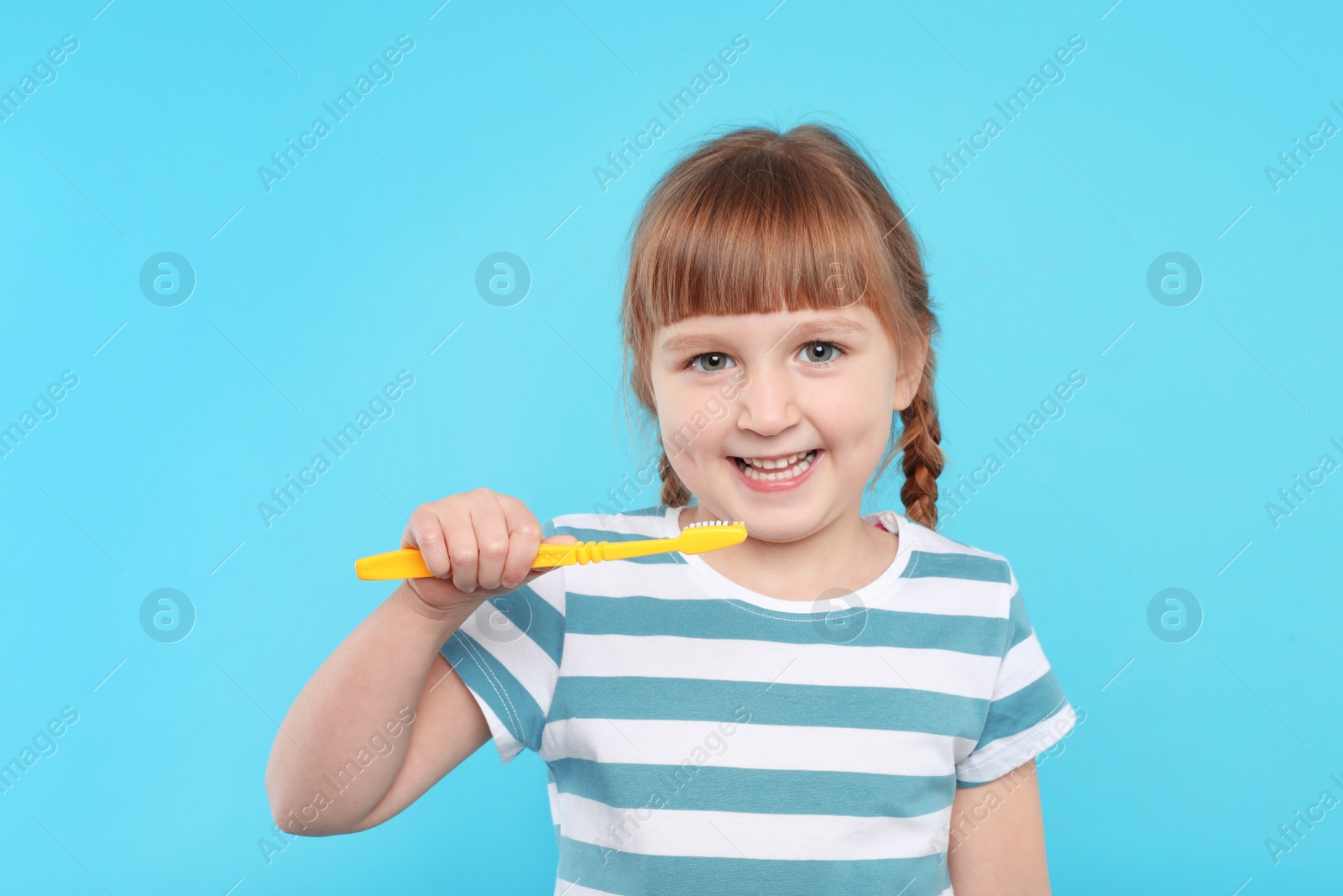 Photo of Little girl brushing teeth on color background