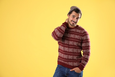 Photo of Portrait of young man in Christmas sweater and hat on yellow background. Space for text