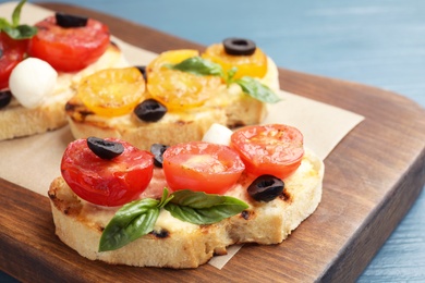 Photo of Delicious tomato bruschettas on wooden board, closeup