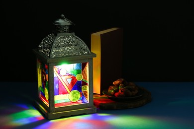 Photo of Decorative Arabic lantern and dates on table against dark background