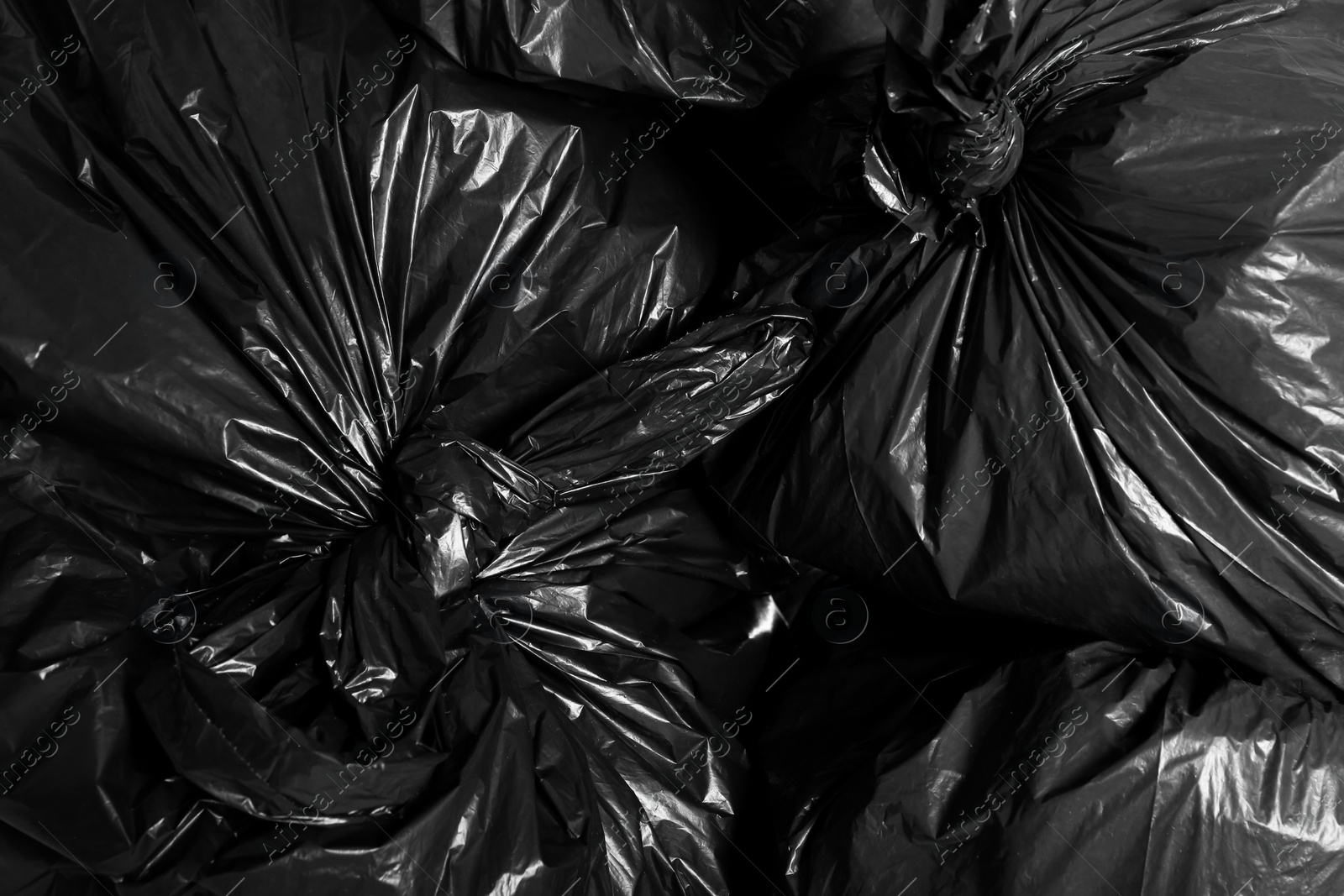 Photo of Black trash bags full of garbage as background, top view