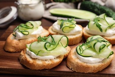 Tasty bruschettas with cucumbers on wooden table, closeup