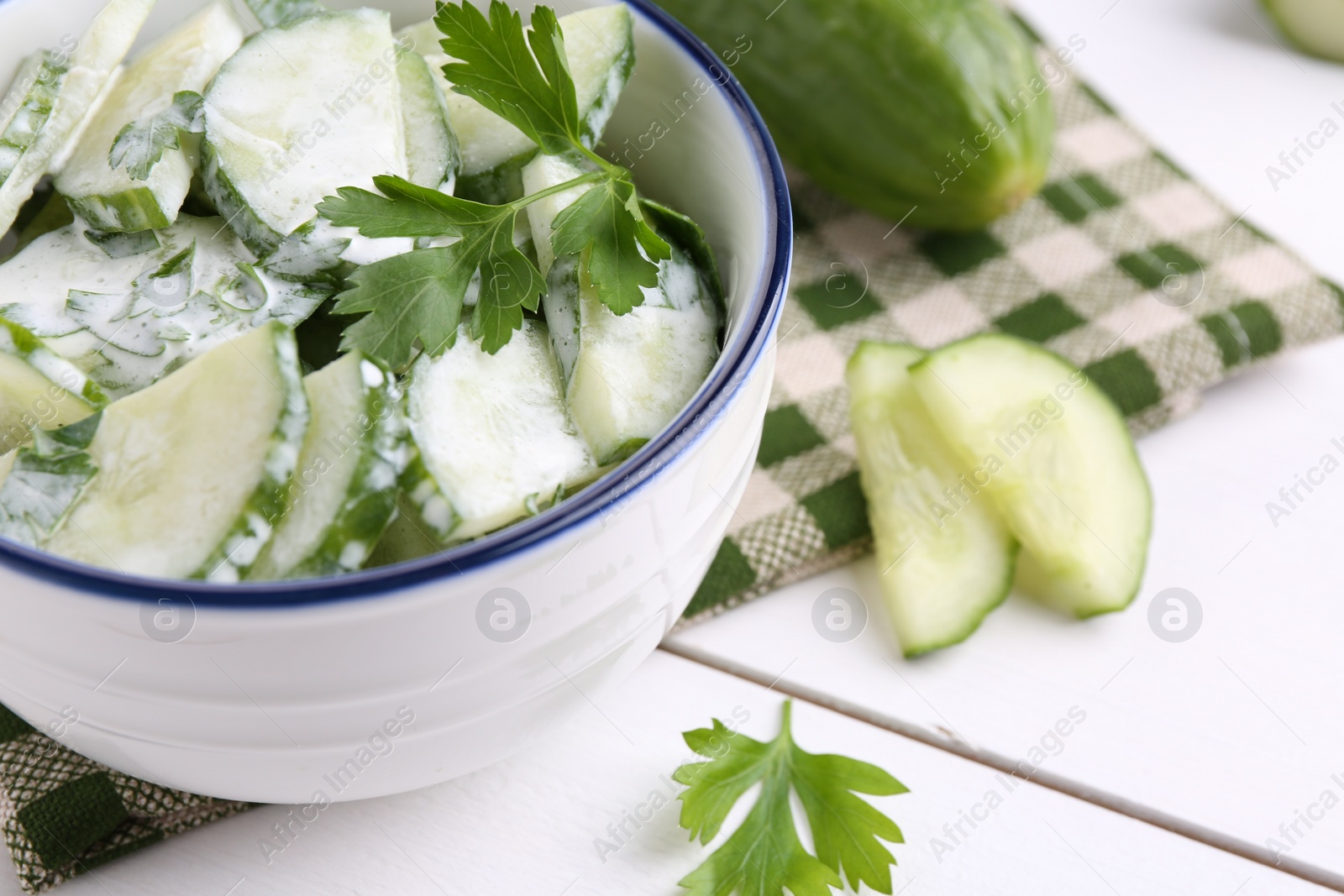 Photo of Delicious cucumber salad in bowl on white table, closeup. Space for text